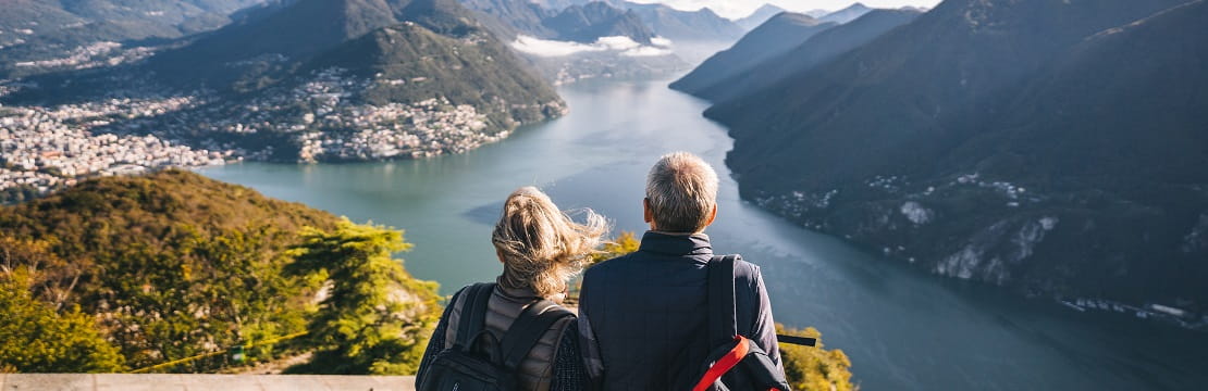 Elderly couple looks over a mountaintop at a scenic view. 